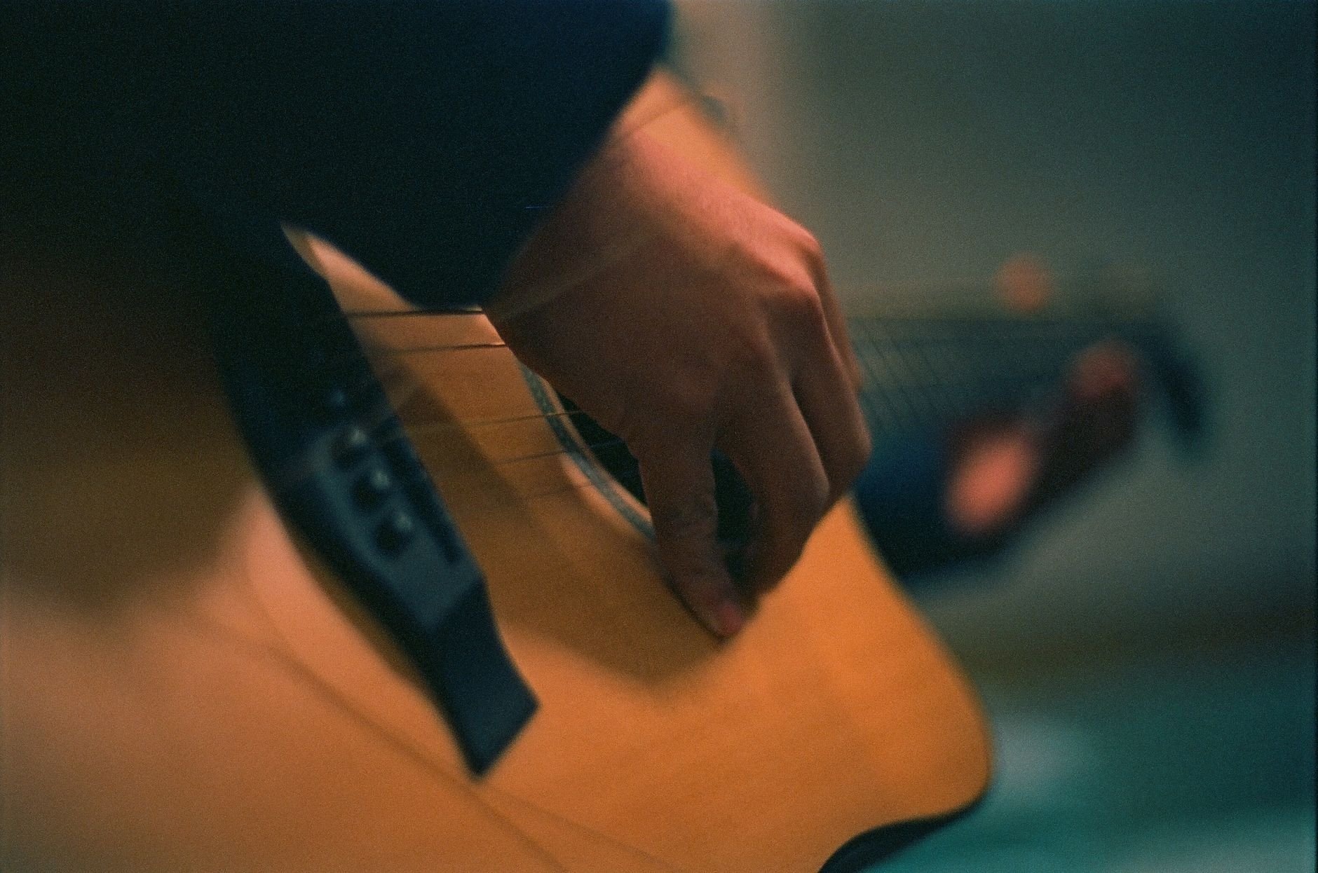 Artistic close-up of a hand strumming an acoustic guitar, creating a warm musical ambiance.